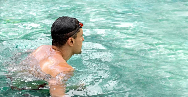 Simmare. Ung atletisk brunett man bär simglasögon i poolen. Panorama-fanan. En hälsosam livsstil. Allvarlig idrottsman mot bakgrund av turkost vatten. Sport och fitness konditionsträning. — Stockfoto