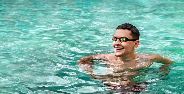 Simmare. Sidovy av leende atletisk man bär simglasögon i poolen. Idrottare mot bakgrund av turkost vatten. Sport och fitness konditionsträning. Panorama banderoll. — Stockfoto