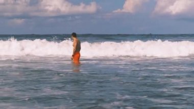 Endonezya 'nın Bali açıklarında öfkeli Hint Okyanusu' nda yüzen atletik adam kameraya beyaz köpüklü büyük sörf dalgaları yaklaşıyor. Aşırı boş zaman..
