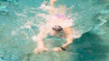 Havuzdaki yüzücü berrak mavi suda serbest yüzme trenleri kullanıyor, yüzmek için gözlük takıyor. Profesyonel atlet, yarışmalar. Sağlıklı yaşam tarzı, spor, kardiyo. Gerçek zamanlı, 4k