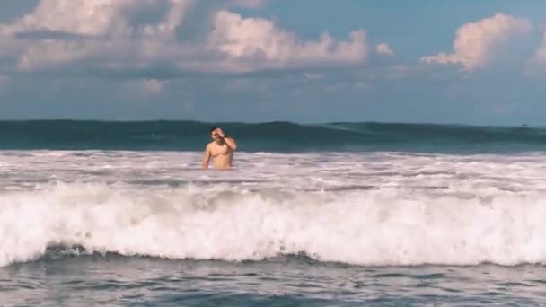 Homem atlético nadando no furioso Oceano Índico ao largo da costa de Bali, na Indonésia, grandes ondas de surf com espuma branca se aproximando da câmera. Lazer extremo. — Vídeo de Stock