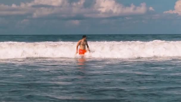 Uomo atletico che nuota nell'infuria dell'Oceano Indiano al largo della costa di Bali in Indonesia, grandi onde da surf con schiuma bianca che si avvicina alla fotocamera. Tempo libero estremo. — Video Stock