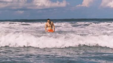 Atletik adam Endonezya 'nın Bali kıyısındaki öfkeli Hint Okyanusu' nda yüzüyor. Beyaz köpüklü büyük sörf dalgaları kameraya yaklaşıyor. Aşırı boş zaman..