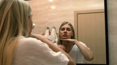 İkinci çene, obezite. 30 'lu yaşlardaki bir kadının portresi çenesinin derisini geriyor, hayal kırıklığına uğramış bir bakışla kameraya bakıyor. Yaşlanma ve görünüş sorunları. Yüz gerdirme, estetik ameliyat