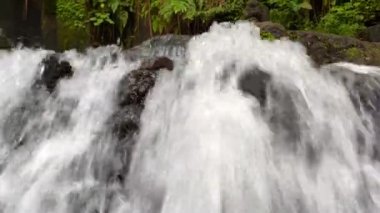 Close-up side view of cascading waterfall rapidly flowing down the rocks in the rainforest. Sumampan Waterfall in Ubud in Bali, Indonesia. 4K Video