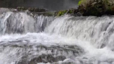 Close-up side view of cascading waterfall rapidly flowing down the rocks in the rainforest. Sumampan Waterfall in Ubud in Bali, Indonesia. 4K Video