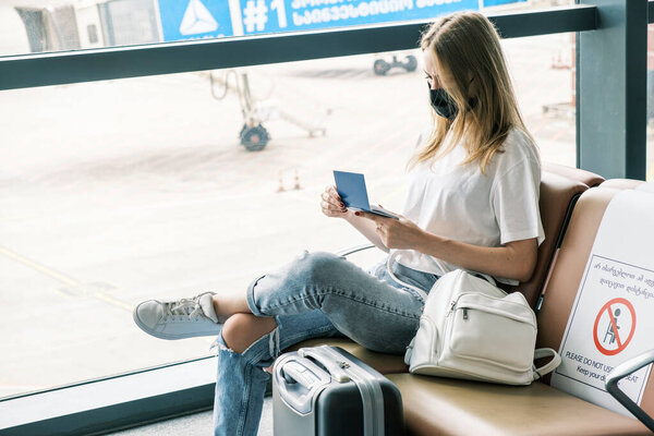 Biometric Ukrainian passport in hands of woman waiting for flight at airport. Citizen of Ukraine is forced to leave her home because of war with Russia. Ukrainian refugees - immigrants abroad.