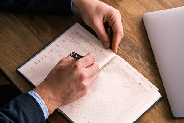 stock image Close up top view of businessman writing in notebook, caucasian male hands holding pen making notes planning new appointments information in organizer personal paper planner at desk.