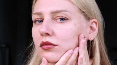 Doğal güzellik ve özgüven. Genç, çekici, mavi gözlü sarışın kadın aynada kırışıklık arıyor. Gençliğin yaşlanması ve korunması. Derinin sağlığı ve gençliği.