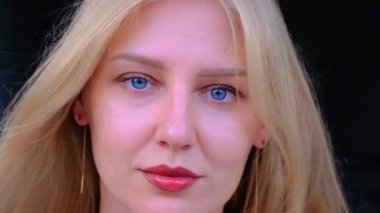 Doğal güzellik ve özgüven. Mavi gözlü çekici sarışın kadın kameraya bakıyor. Gençliğin yaşlanması ve korunması. Sağlık ve cilt gençliği. Rüzgarda sallanan saçlar
