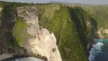 Nusa Penida island, Kelingking beach. Top view aerial shot of a sandy clean beach with clear blue and turquoise water. Rocks and waves with white foam