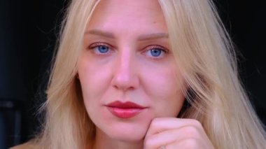 Güzel kadınların yüzlerine yakın çekim. Genç mavi gözlü, gülümseyen sarışın kız kameraya bakıyor. Ortak yüz ve vücut için yaşlanmayı önleyici bakım. Gençliğin uzaması ve cildin tazeliği