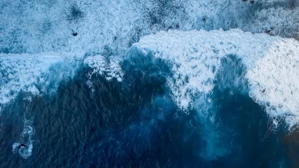 Beautiful texture of dark ocean waves of high power with white foam. Drone filming breaking surf in Indian Ocean on Nusa Penida island. Frames from birds eye view. Big wave in Bali. Capital of surfer