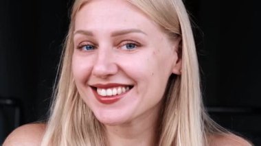 Güzel kadınların yüzlerine yakın çekim. Genç mavi gözlü, gülümseyen sarışın kız kameraya bakıyor. Ortak yüz ve vücut için yaşlanmayı önleyici bakım. Gençliğin uzaması ve cildin tazeliği