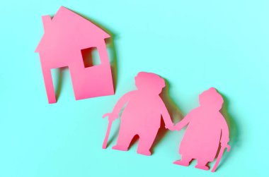 İki yaşlı insanın parlak kırmızı figürleri ve renkli arka planda bir ev. Yaşlıların konut sorunları kavramı.