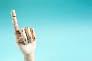 Mavi arka planda, parmağını kaldırmış tahta bir el. Kavramsal jest uyarısı veya dikkat