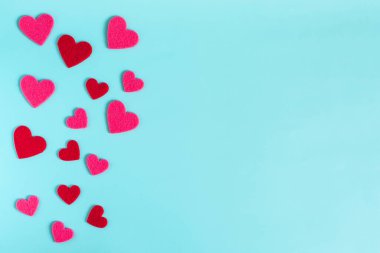Açık mavi parlak arkaplan, kırmızı ve pembe renkli kalpler.