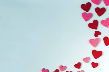 Açık mavi parlak arkaplan, kırmızı ve pembe renkli kalpler.