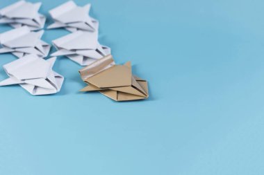 Liderlik kavramı. Renkli arka plandaki tanımlanamayan beyaz arabalarla karşılaştırıldığında bej renkli kağıt araba önde gidiyor
