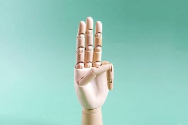 Tahta el hareketi üç parmağın havada olduğunu gösteriyor. Konsept, arka planda üç numarayı yakın planda gösteren tahta bir el.