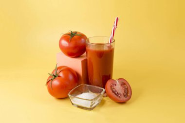 Domates dekoru, tuz ve portakal küpünün üzerinde portakal suyu bulunan cam bir kabın içindeki domates suyu.