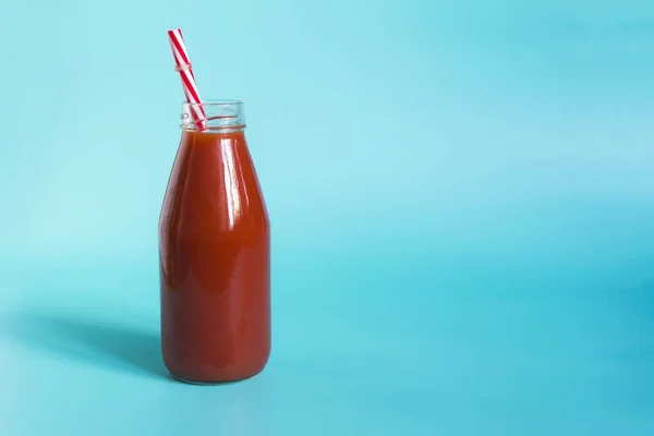 Tomatensaft Einer Durchsichtigen Flasche Mit Rotem Schlauch Auf Blauem Hintergrund — Stockfoto