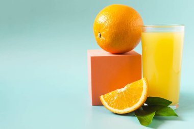 Şeffaf bardakta portakal ve yeşil yapraklı taze portakal suyu.