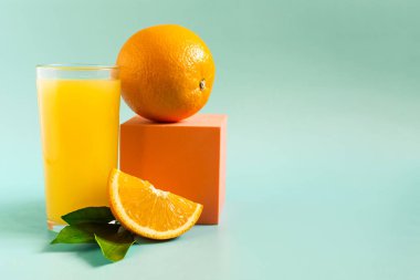 Şeffaf bardakta portakal ve yeşil yapraklı taze portakal suyu.