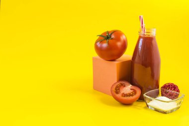 Taze domates suyu, domates dekoru, tuz ve sarı arkaplan fotokopi alanı üzerine renkli bir küp.