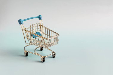 Mavi arka plandaki bir süpermarketten mavi boş metal sepet, yakın plan ticaret konsepti.