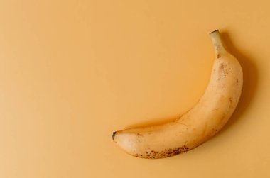 Turuncu arka planda taze turuncu muz. Renkli bir arkaplan kopyalama alanı üzerinde muz yakın plan