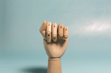 A wooden android hand with fingers clenched into a fist close-up. Conceptual hand gesture