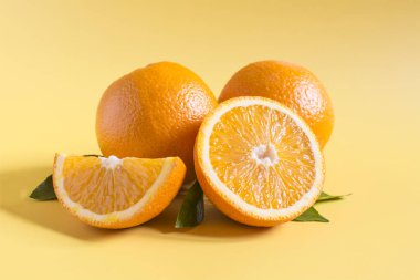 Bright juicy oranges and green leaves on an orange background close-up