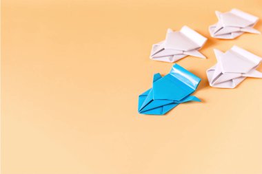 Rekabet konsepti. Beyaz origami makinelerinin önünde renkli kağıttan yapılmış Origami makinesi