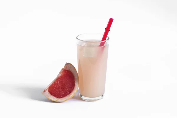 グレープフルーツジュースとグレープフルーツのスライスを白い背景に ガラスの中のグレープフルーツジュース白い背景に赤いチューブでクローズアップ — ストック写真