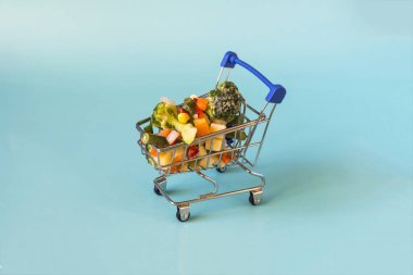 Hızlı dondurulmuş ürünler kullanma kavramı. Açık mavi arka planda metal bir sepette donmuş sebzeler..