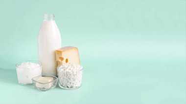 Süt ürünleriyle reklam pankartları. Süt, kefir, ekşi krema, peynir, tereyağı ve süzme peynir açık arkaplan üzerinde cam bir kapta