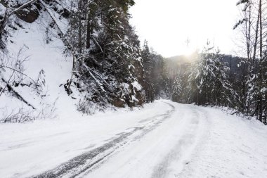 Karla kaplı yollar ve dağ yamaçları orman kışı manzarasıyla kaplı..