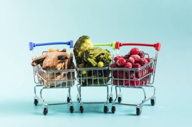 Donmuş yeşil sebzeler, böğürtlen ve mantar şampiyonları. Bakkal sepetlerinde dizilmiş buz kristalleri ve mavi arka planda yakın plan çekimleri..