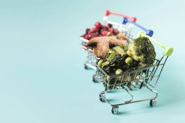 stock image Frozen green vegetables, berries and mushrooms champignons with ice crystals in metal baskets on a light background of kopi space