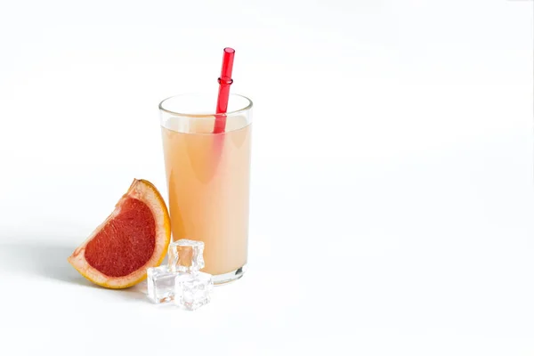 自然なグレープフルーツジュースと白い背景にグレープフルーツのスライスは テキストのための場所です ガラスの中のグレープフルーツジュース明るい赤チューブ自然光 — ストック写真