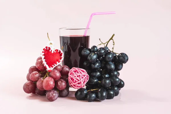 赤と黒のブドウの枝と赤のハートのクローズアップとブドウジュースの透明なガラス — ストック写真