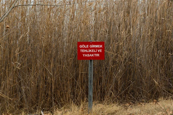 Red warning sign by the lake:  \