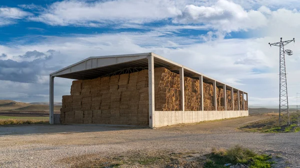 Structure with concrete pillars and concrete roof used to store straw bales.