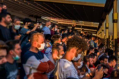 Odaklanamayan bulanık yüzlü seyirciler stadyumda ellerinde cep telefonuyla maçı izliyorlar..