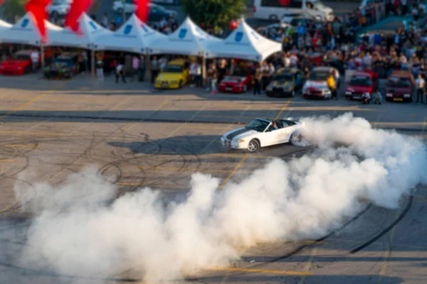 Araba sürüklenme gösterisinin bulanık ve odaklanmamış üst görüntüsü.