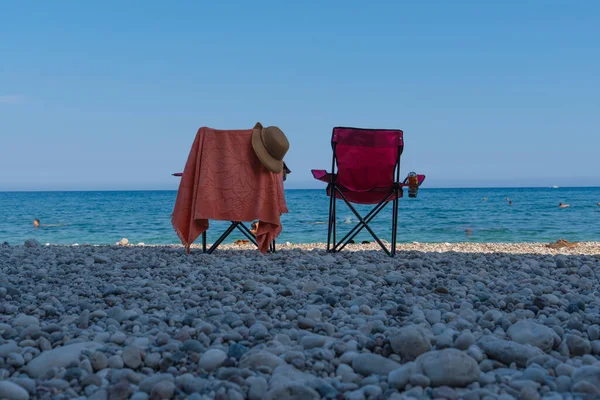 Two beach chairs by the sea. Back rear view of chairs and sea and sky in background.