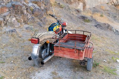 Elazig, Türkiye-18 Eylül 2020: Kayalık bölgeye park edilmiş eski model motosikletin arka manzarası.