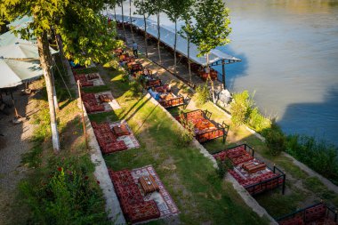 Diyarbakır, Türkiye - 17 Eylül 2020: Halk, Dicle Nehri üzerindeki tarihi köprü Ten Eyed Köprüsü 'nün (On Gozlu Kopru in Turkish) yanındaki doğu tarzı kafe restoranının keyfini çıkarıyor.