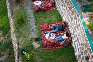 Diyarbakır, Türkiye - 17 Eylül 2020: Halk, Dicle Nehri üzerindeki tarihi köprü Ten Eyed Köprüsü 'nün (On Gozlu Kopru in Turkish) yanındaki doğu tarzı kafe restoranının keyfini çıkarıyor.